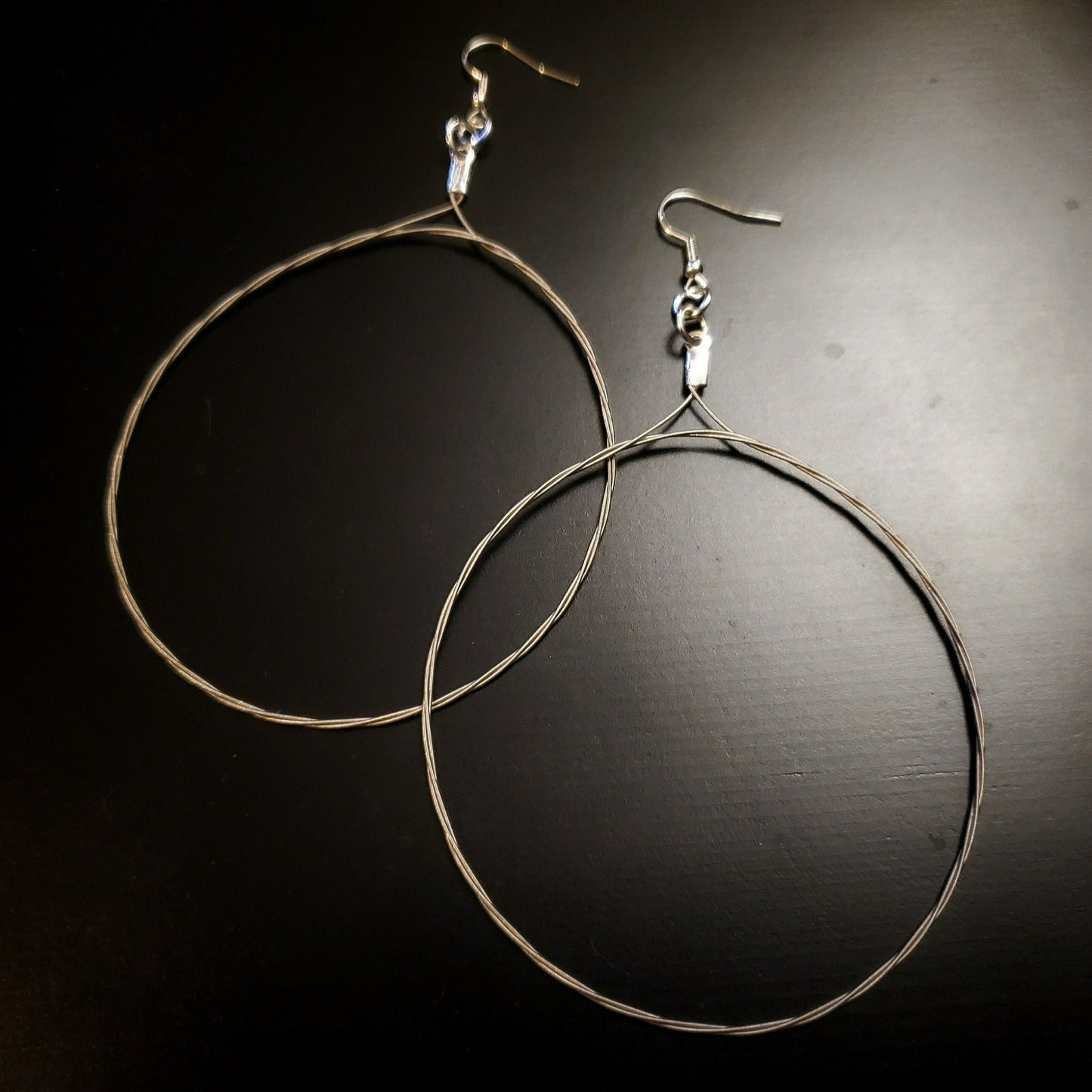 pair of large hoop style earrings made from upcycled guitar strings - black and grey background