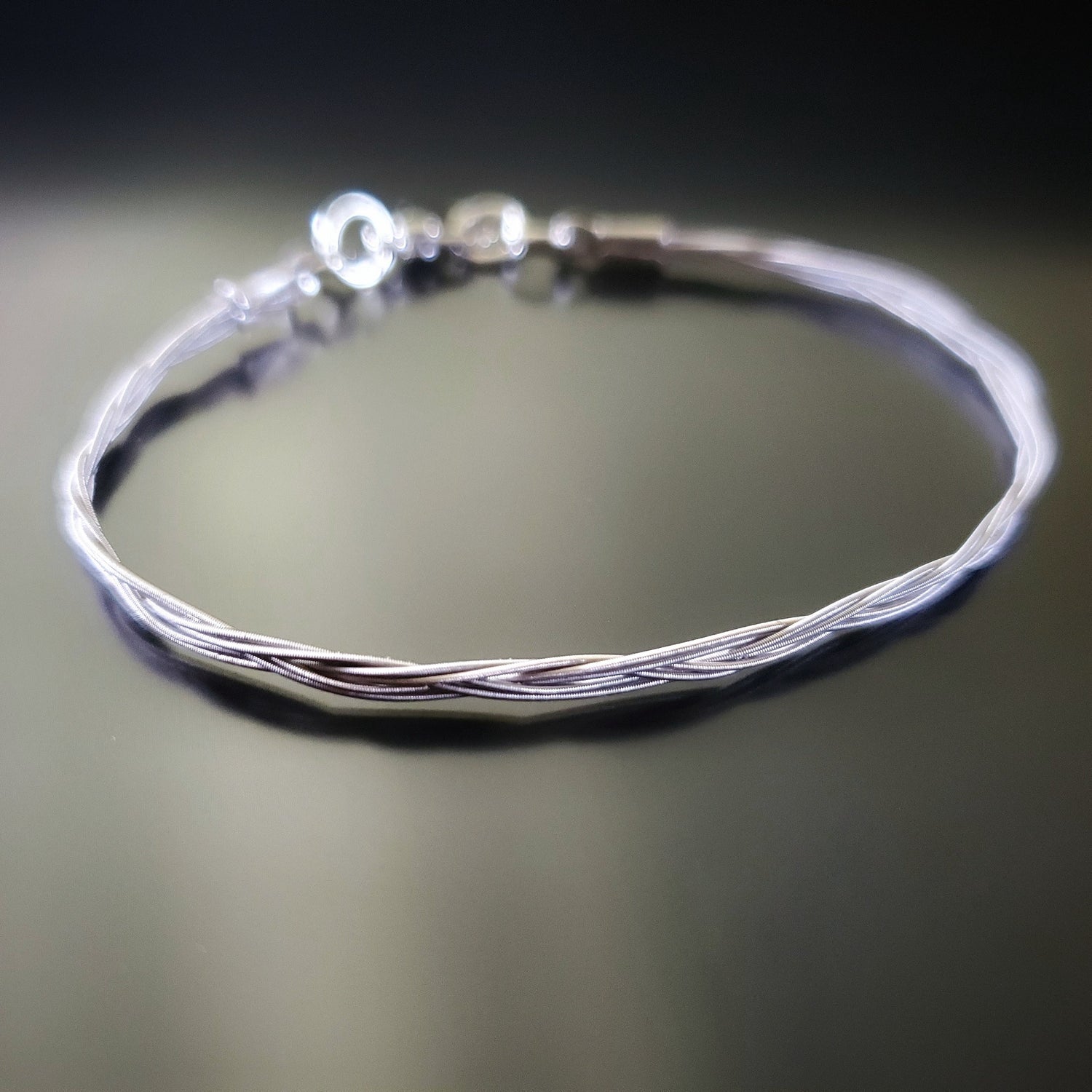 silver banjo string bracelet on a black background