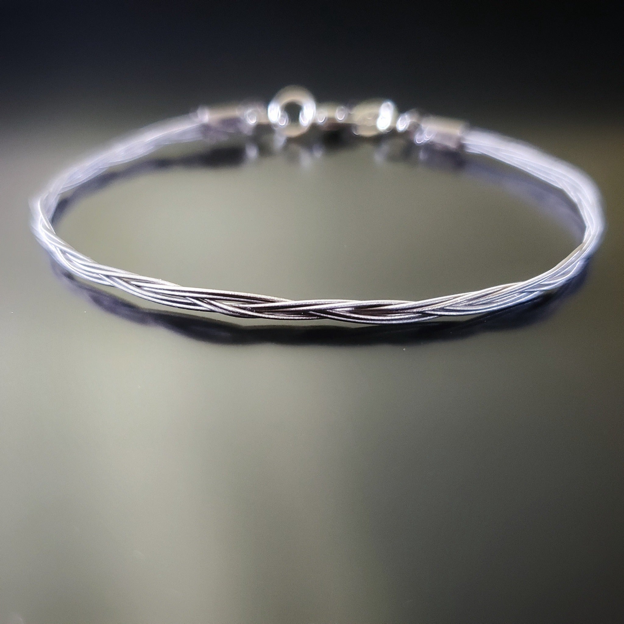 silver banjo string bracelet on a black background