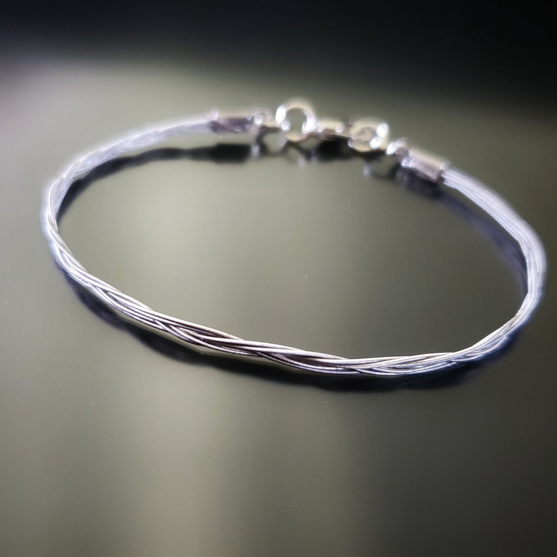 silver banjo string bracelet on a black background