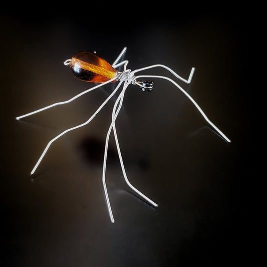 spider sculpture made from upcycled guitar strings and an orange glass bead