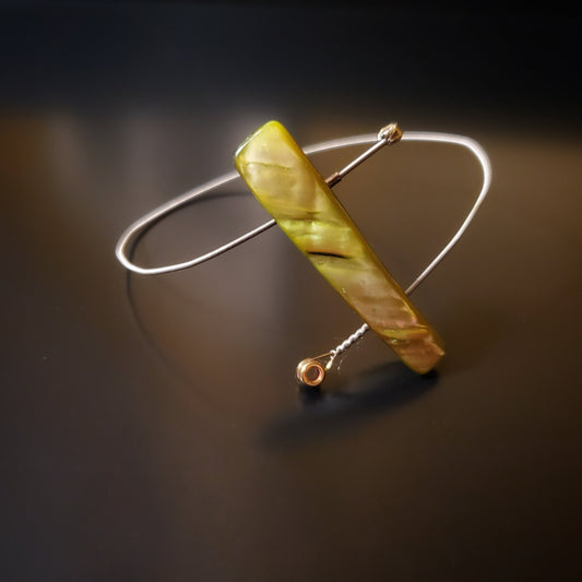 spiral style bangle bracelet made from an upcycled guitar string and a piece of shell in the shape of a rectagle