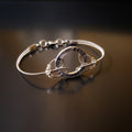 bracelet made from upcycled guitar strings connected to a silver hoop shaped charm with the word HOPE etched 3x on it