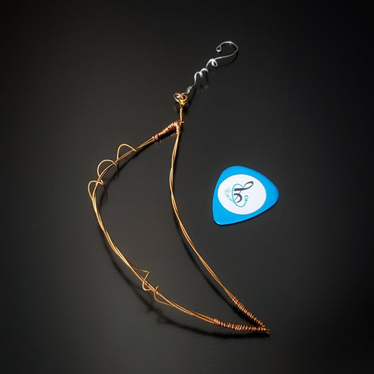moon shaped Christmas ornament made from an upcycled guitar string next to a blue guitar pick