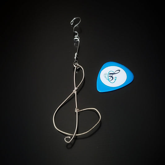 Christmas ornament in the shape of a treble clef, made from an upcycled guitar string - on the left is a blue guitar pick 
