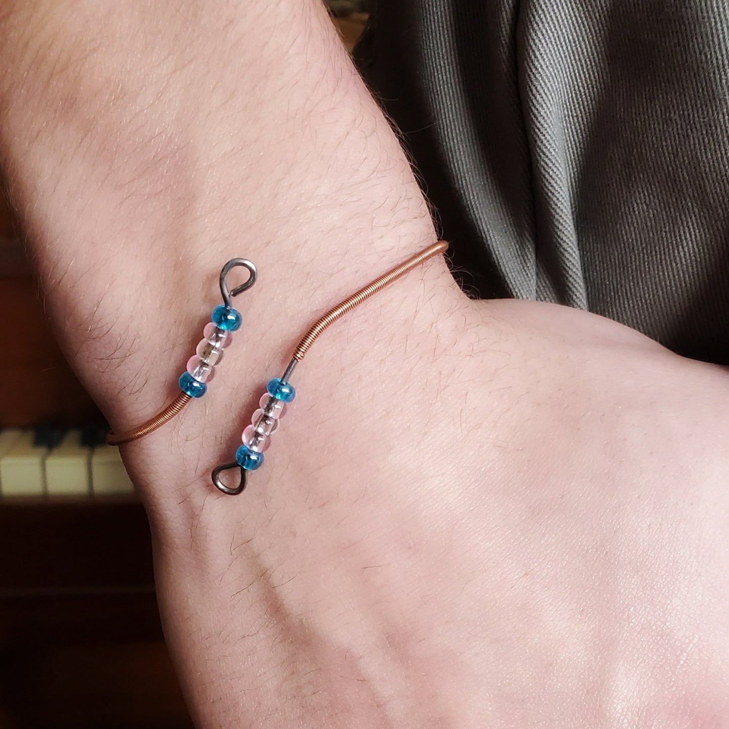 wrist with bracelet with beads representing the colours of the trans pride flag 