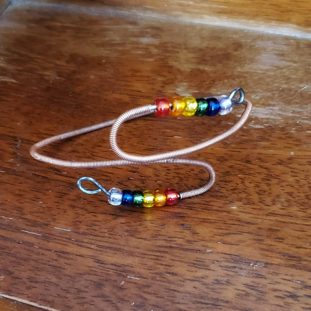 cuff style bracelet with beads representing the LGBTQ pride flag