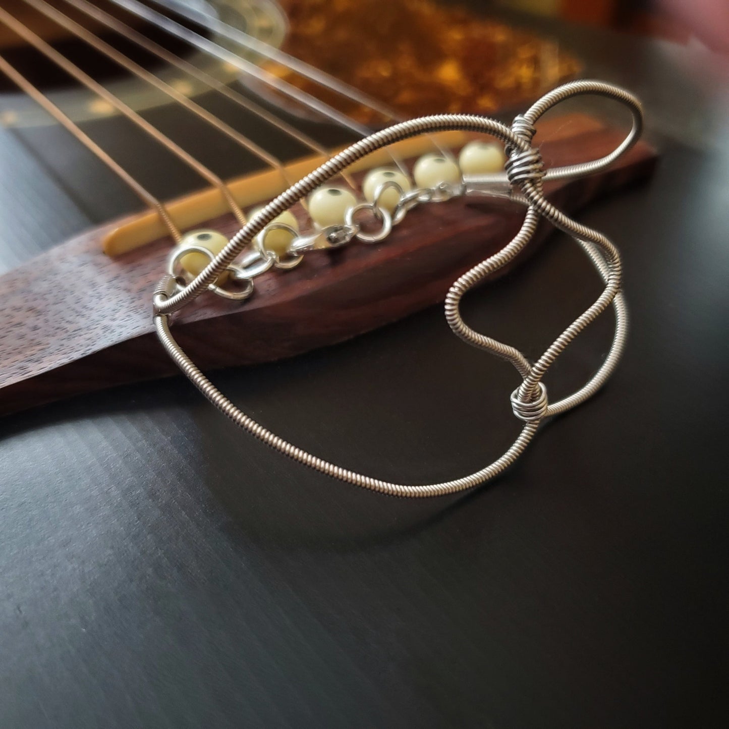 guitar string bracelet in the shape of a heart, sitting on a guitar