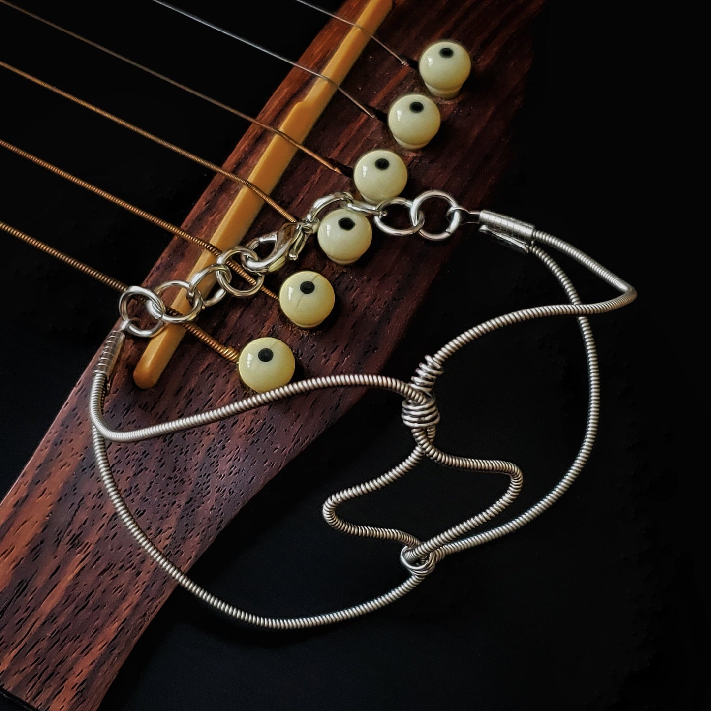 guitar string bracelet in the shape of 2 hearts, sitting on a guitar