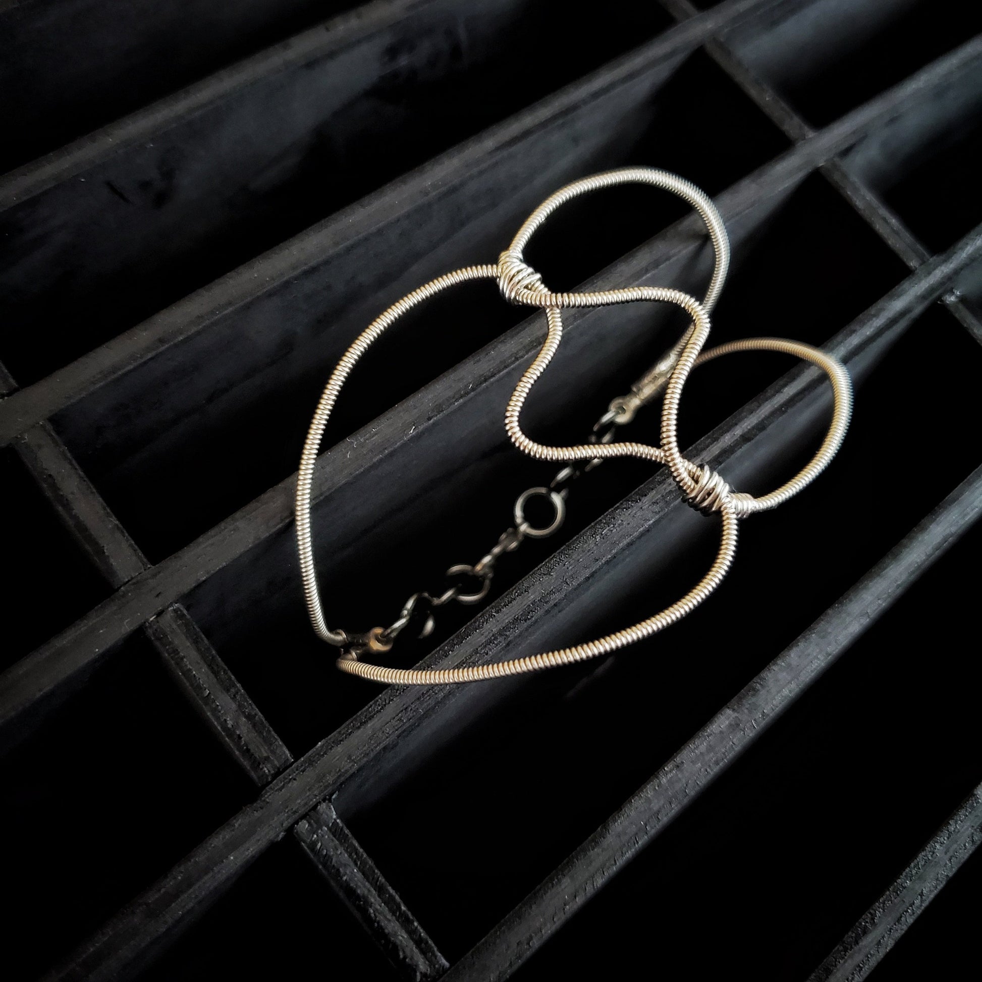 guitar string bracelet in the shape of a heart black background