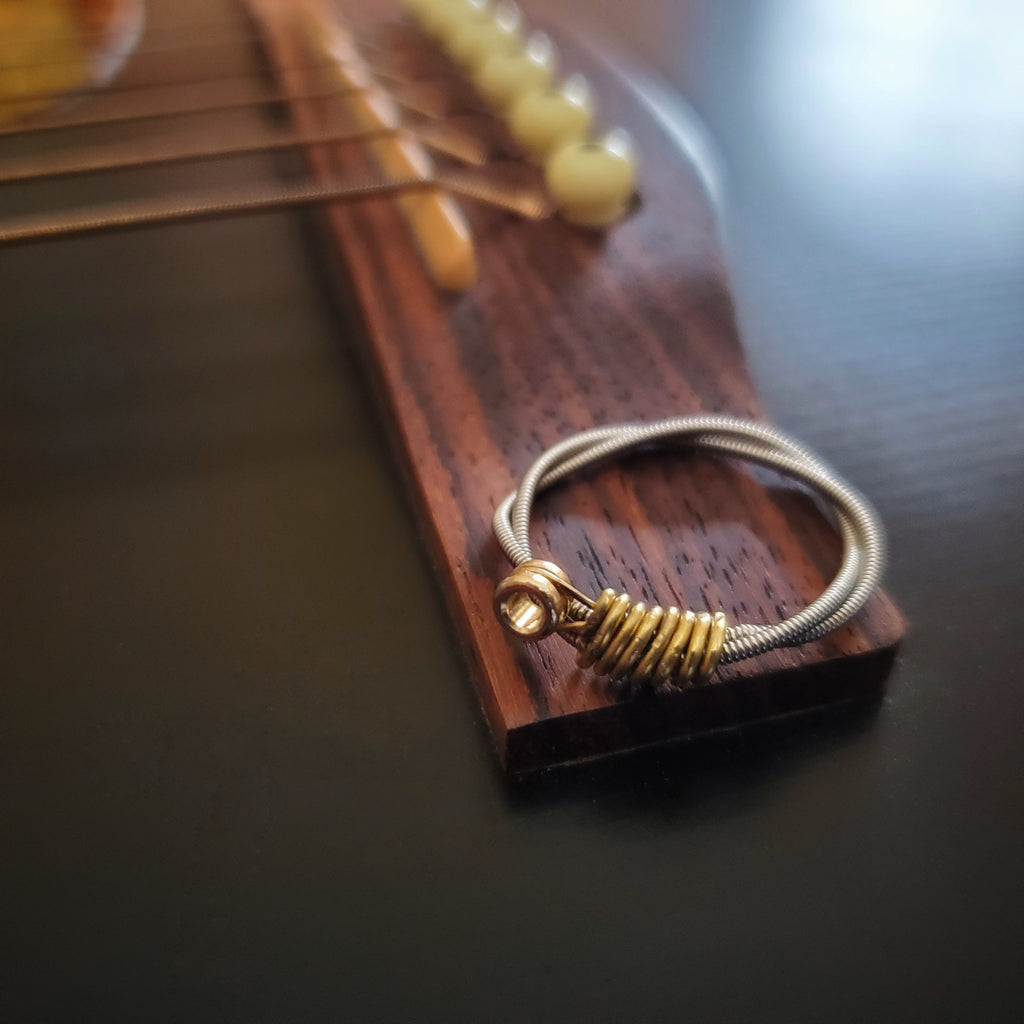 Bague argentée en corde de guitare avec bout doré