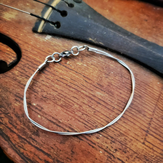 upcycled violin string bracelet sitting on an old violin