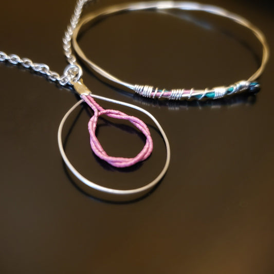 bangle style bracelet and necklace with pink and silver colours on black background