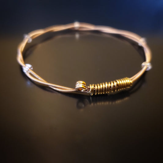copper coloured bangle style guitar string bracelet with clear glass beads with black background