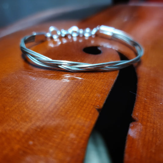 upcycled cello string unisex silver bracelet lying on the body of a cello