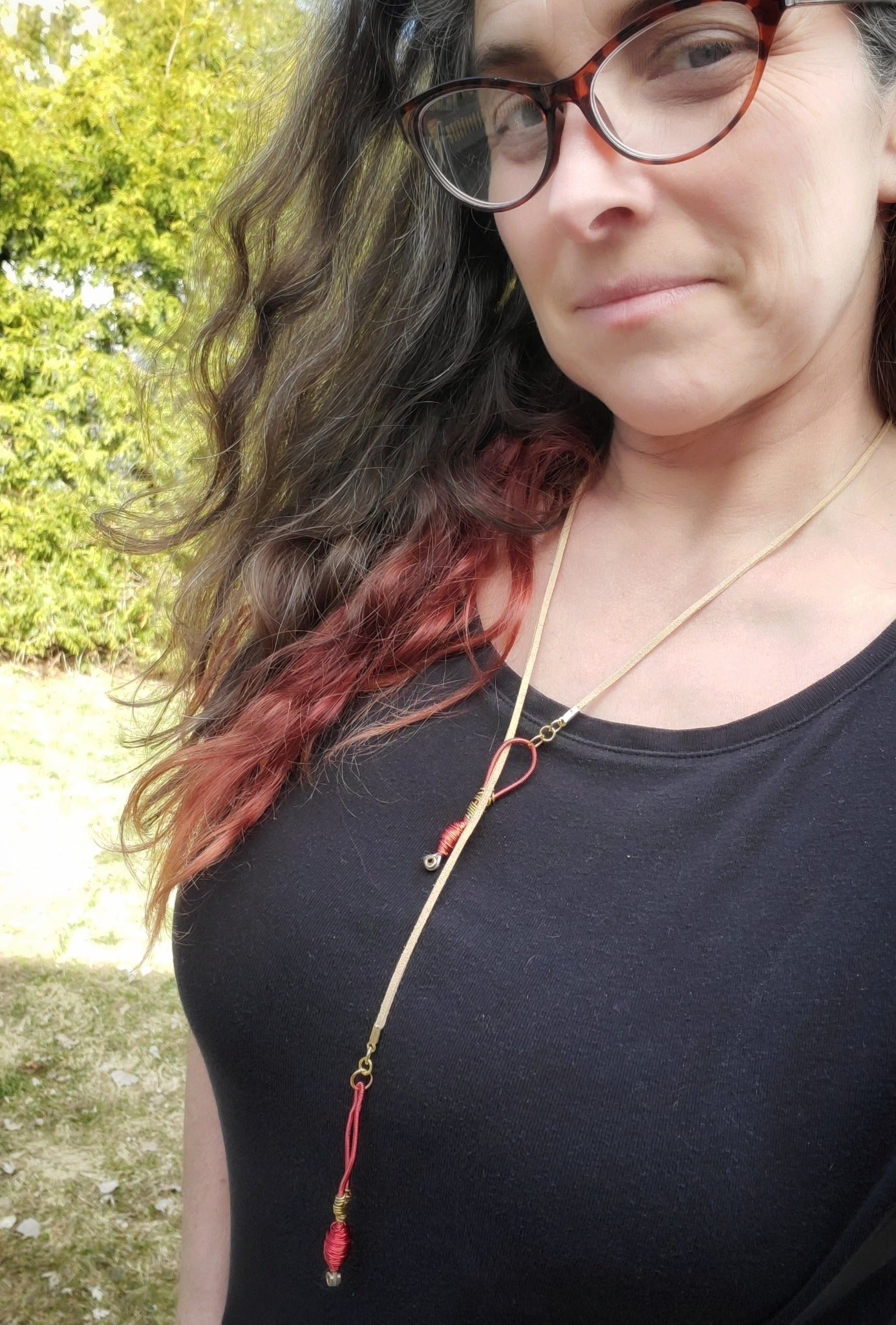 woman with long hair and glasses wearing an upcycled harp string and genuine suede necklace