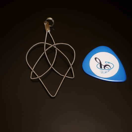 Celtic Heart and Triquetra Knot Guitar String Pendant beside a blue guitar pick