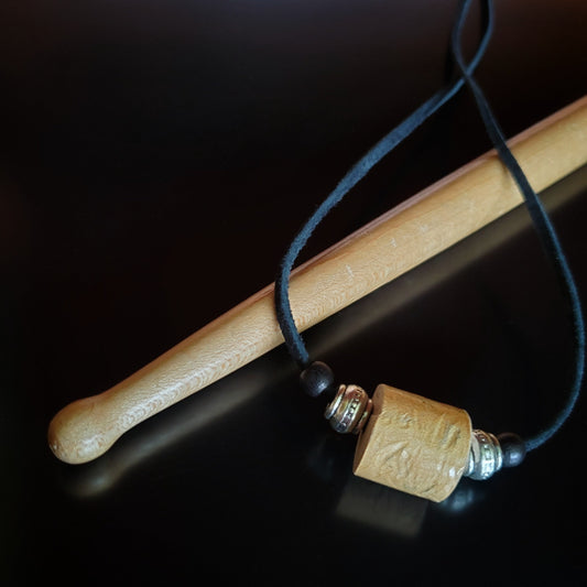 Upcycled Drumstick and Black Suede Necklace With Accented Silver Bead lying on a drumstick