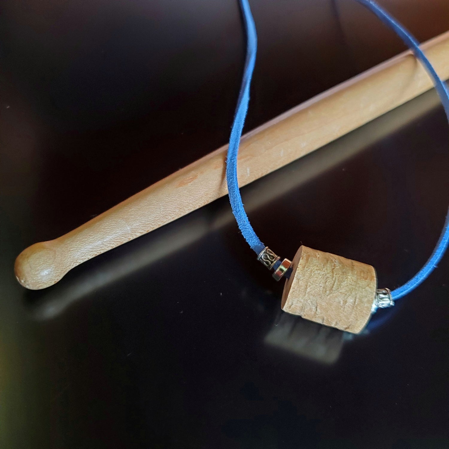 necklace made from a piece of drumstick sitting and blue faux-suede cord on a drumstick