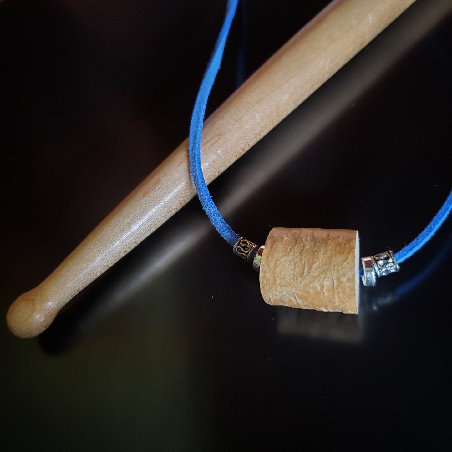 necklace made from a piece of drumstick sitting and blue faux-suede cord on a drumstick