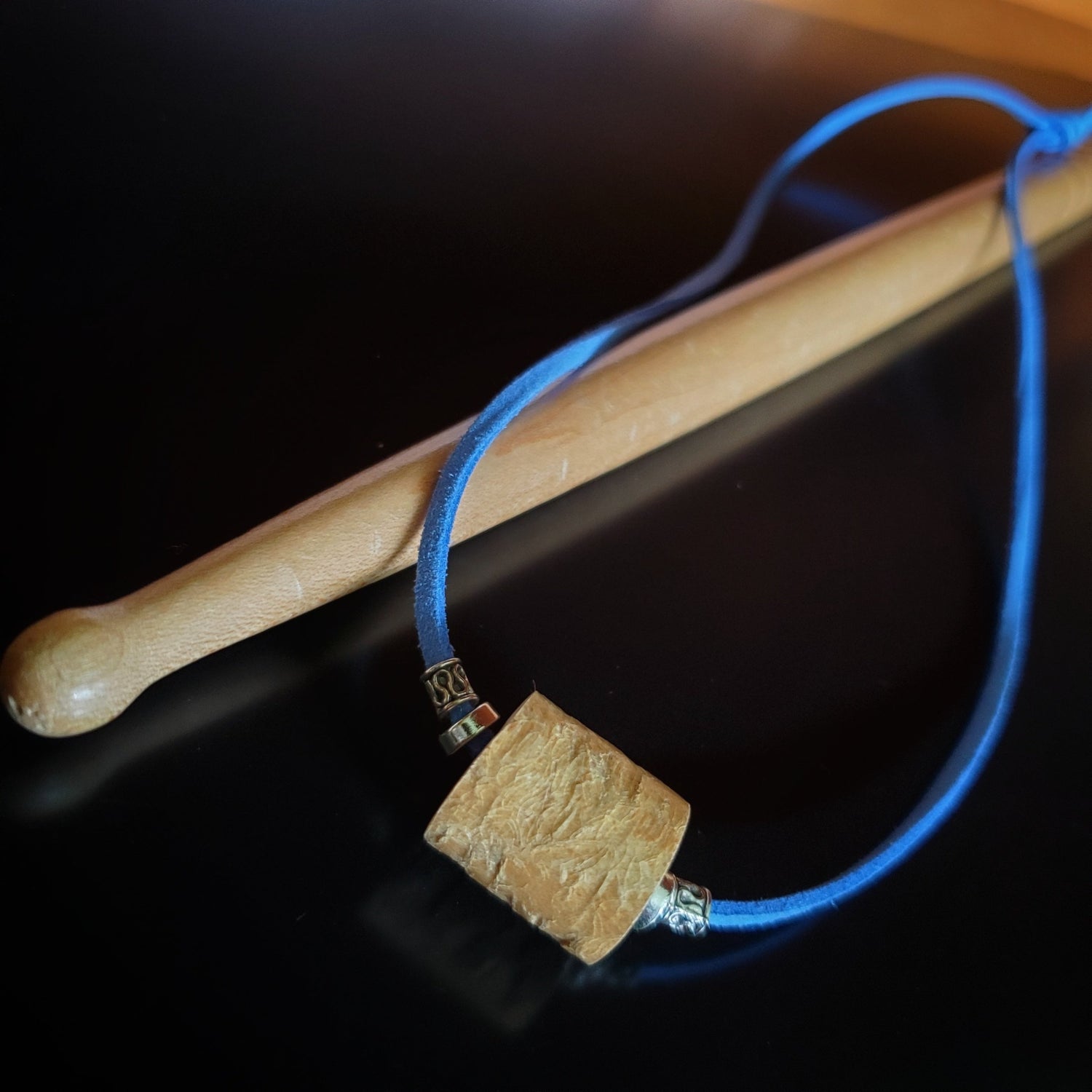 necklace made from a piece of drumstick sitting and blue faux-suede cord on a  drumstick