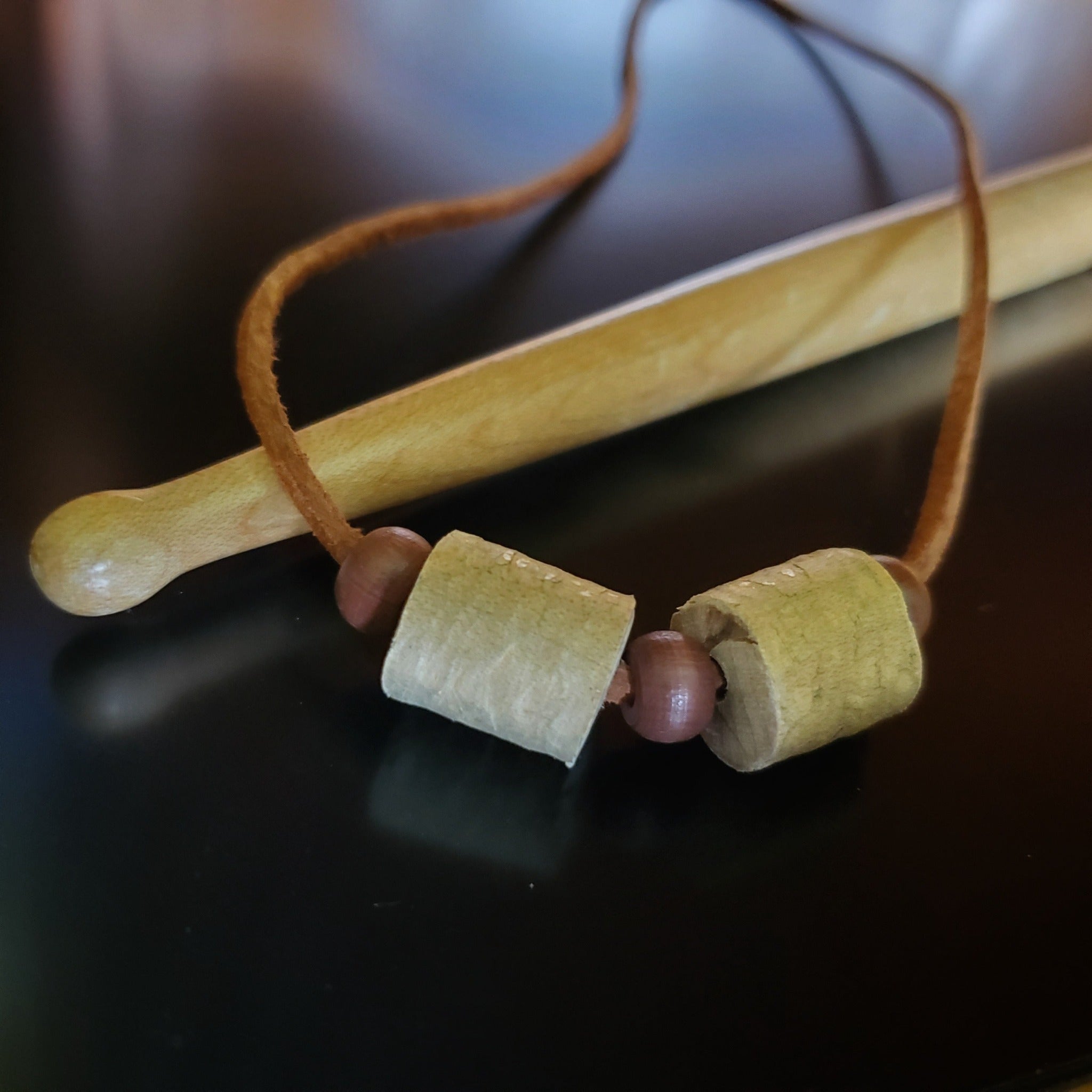 Upcycled Double Drumstick Beads and Brown Suede Necklace With Wooden Beads lying on a drumstick