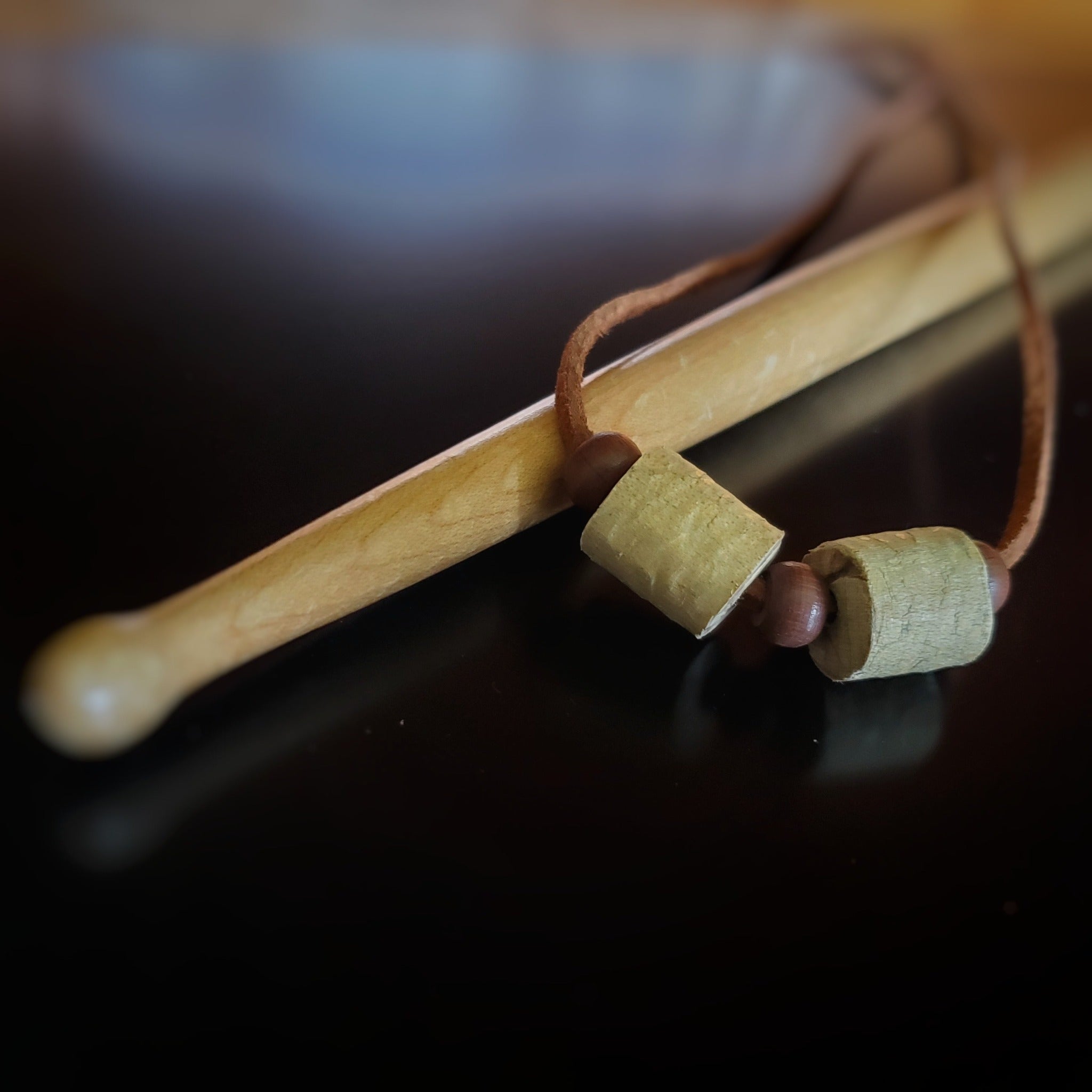 Upcycled Double Drumstick Beads and Brown Suede Necklace With Wooden Beads lying on a drumstick