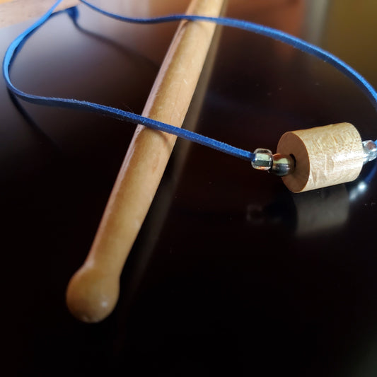 Upcycled Drumstick and Blue Faux-Suede Necklace With Smooth Silver Beads lying on a drumstick