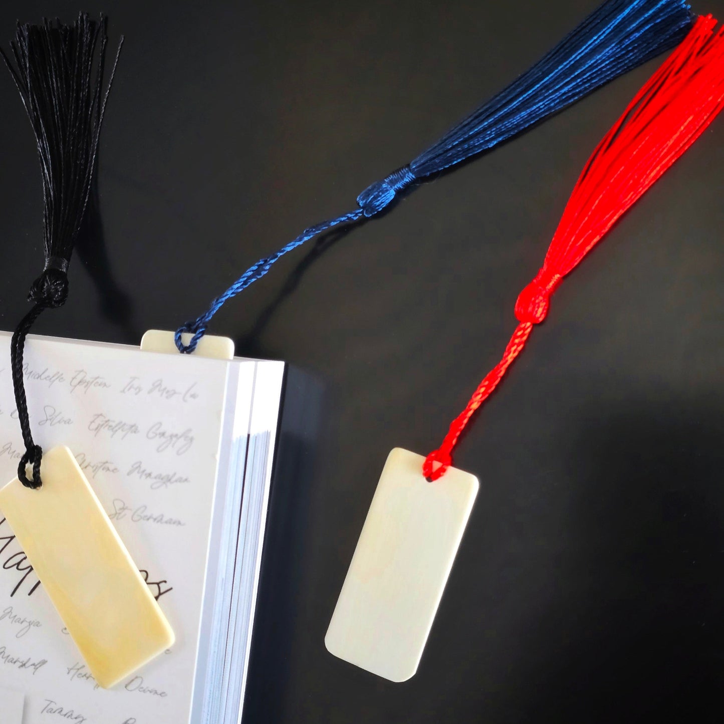 3 ivory piano key bookmarks various colours in and beside a book