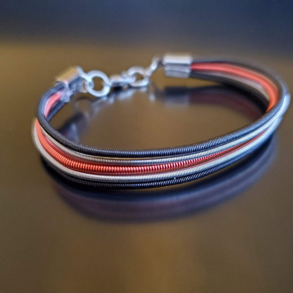 Black Silver and Red Upcycled Harp String Bracelet on dark background