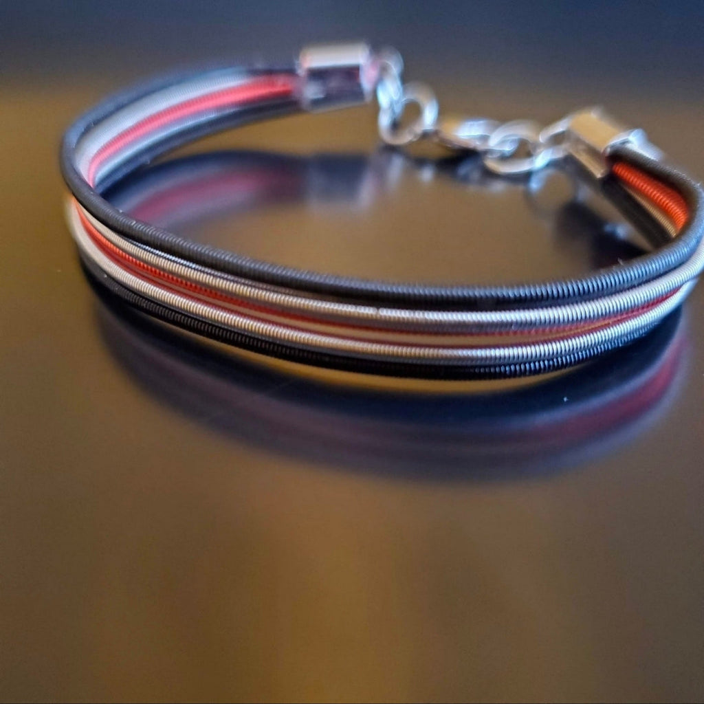 Black Silver and Red Upcycled Harp String Bracelet on dark background side view