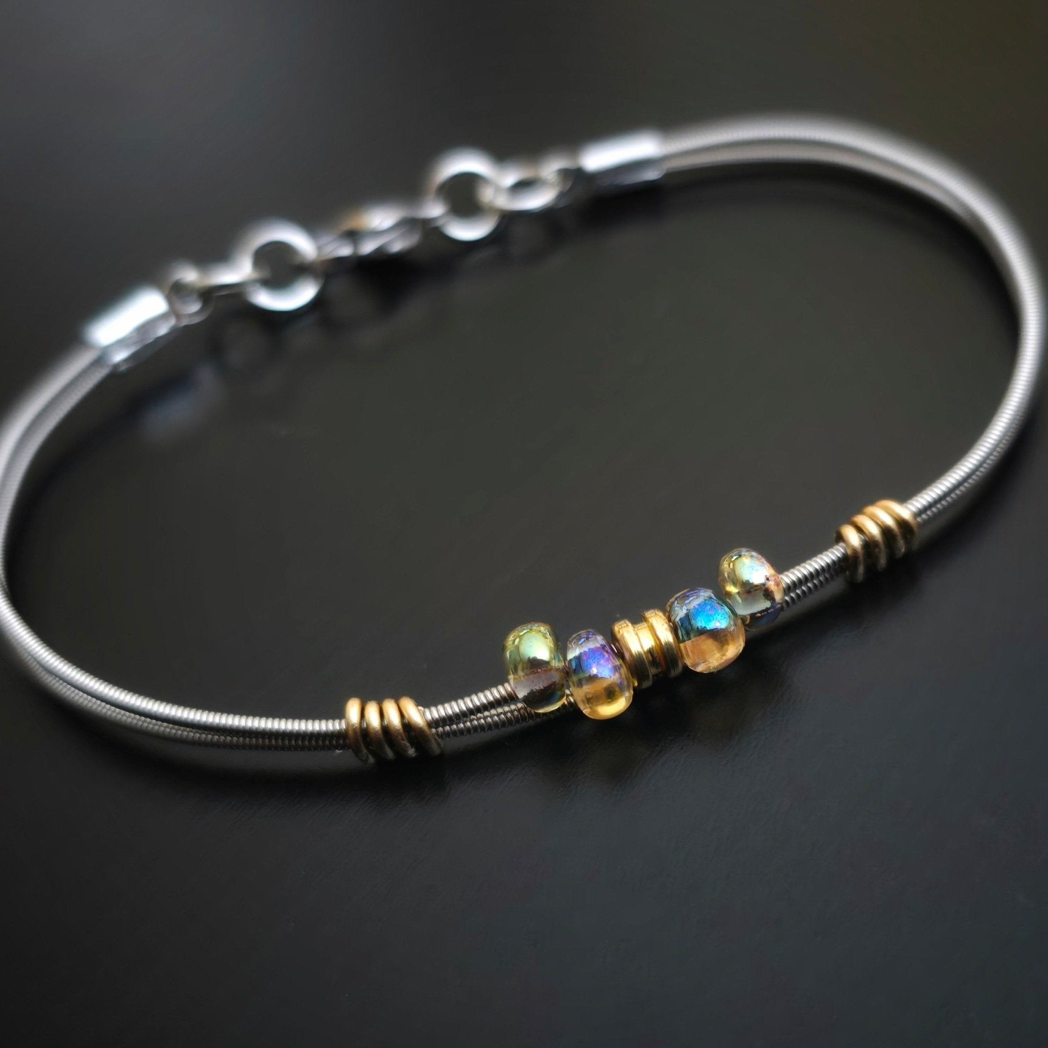 Bright iridescent beaded guitar string bracelet on black background