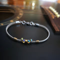 Bright iridescent beaded guitar string bracelet on black guitar