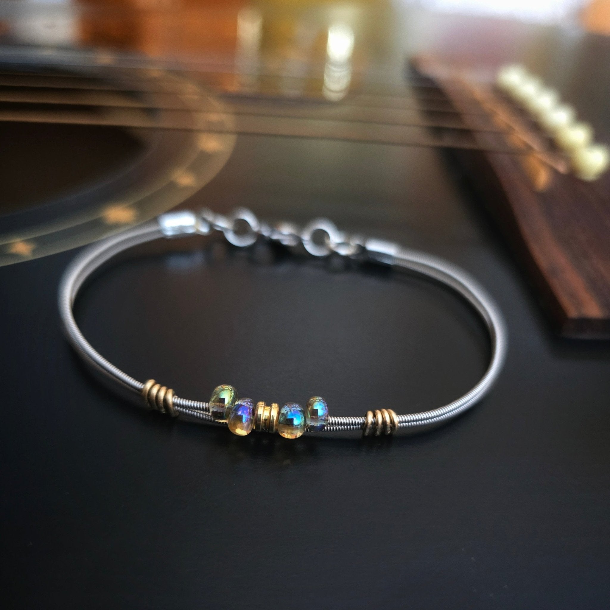 Bright iridescent beaded guitar string bracelet on black guitar