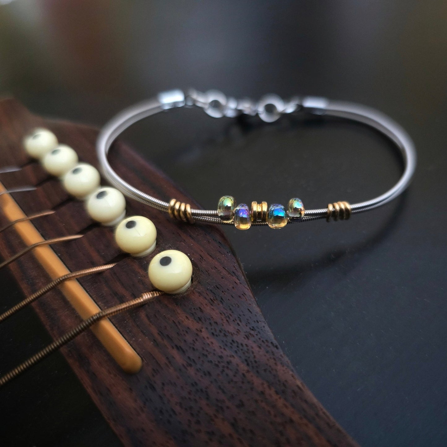 Bright iridescent beaded guitar string bracelet on guitar