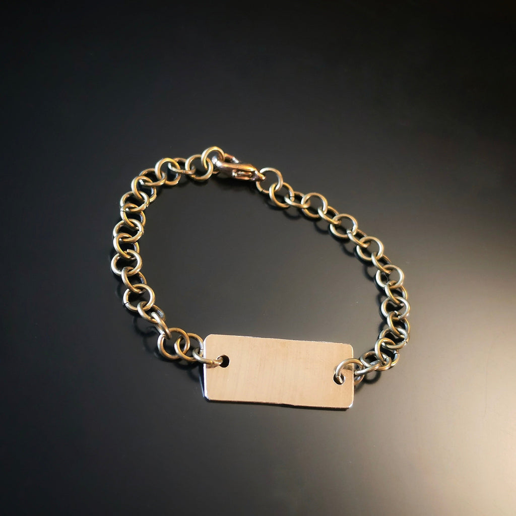 Chain Bracelet with a piece of cymbal on a dark reflective surface.
