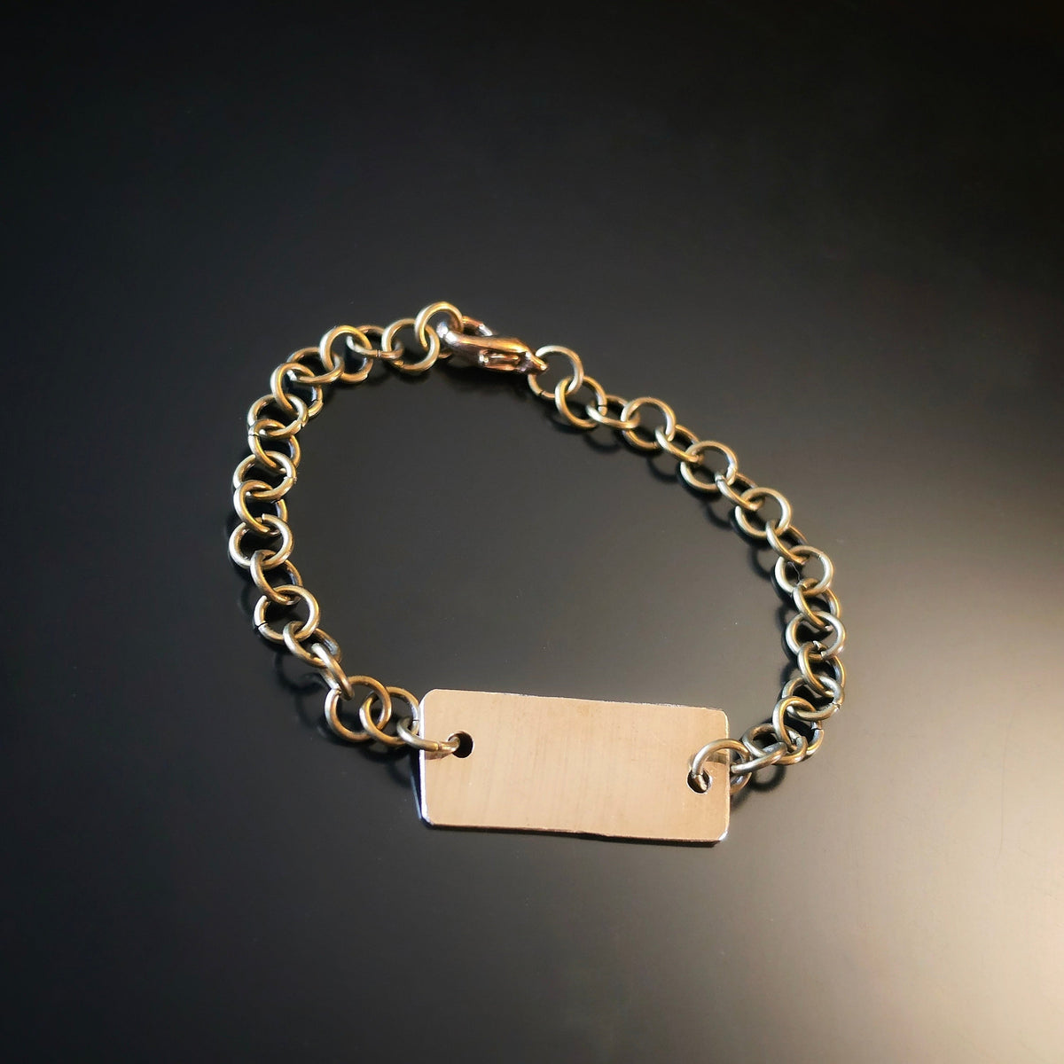 Chain Bracelet with a piece of cymbal on a dark reflective surface.