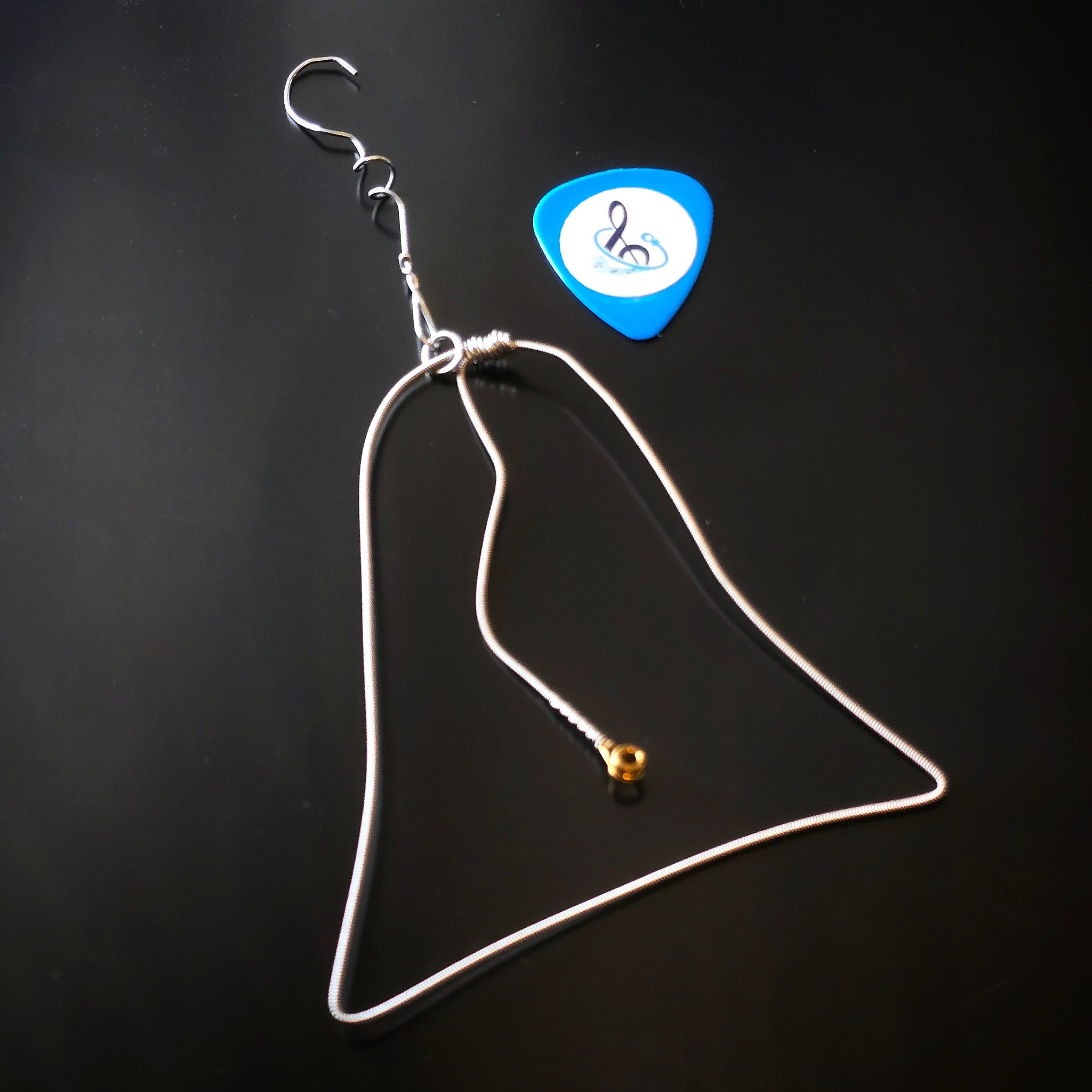 Christmas Bell Guitar String Ornament with blue guitar pick on dark background