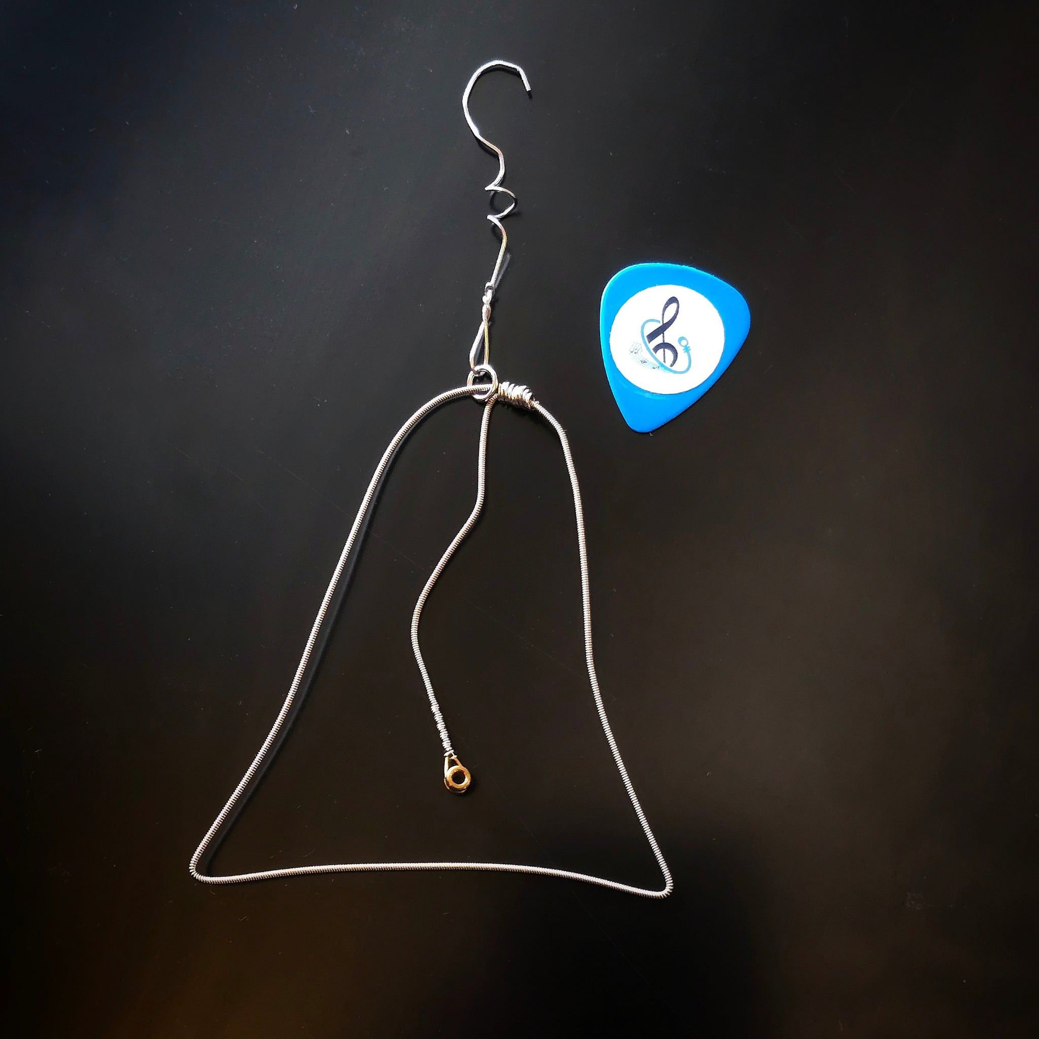 Christmas Bell Guitar String Ornament with blue guitar pick on dark background