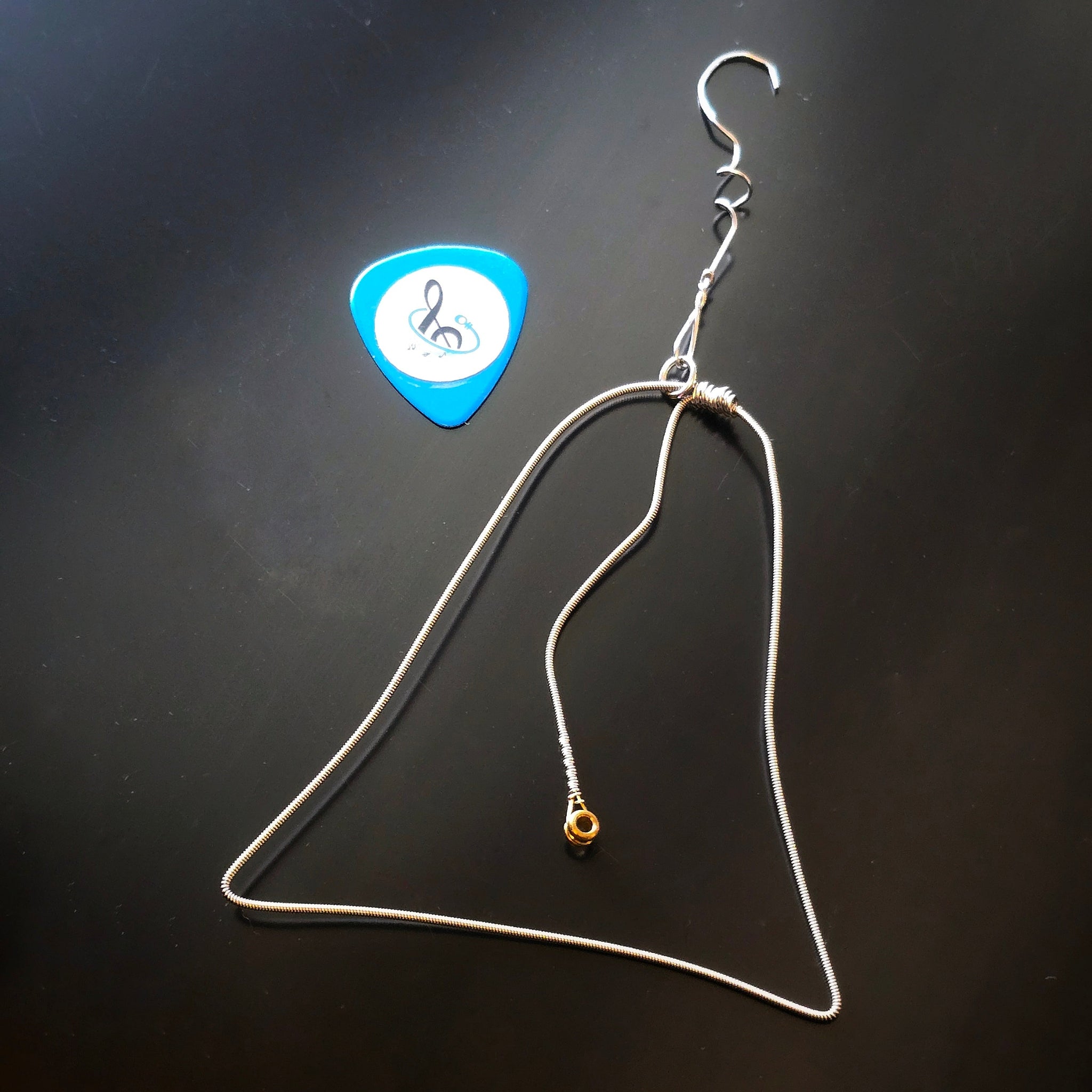 Christmas Bell Guitar String Ornament with blue guitar pick on dark background