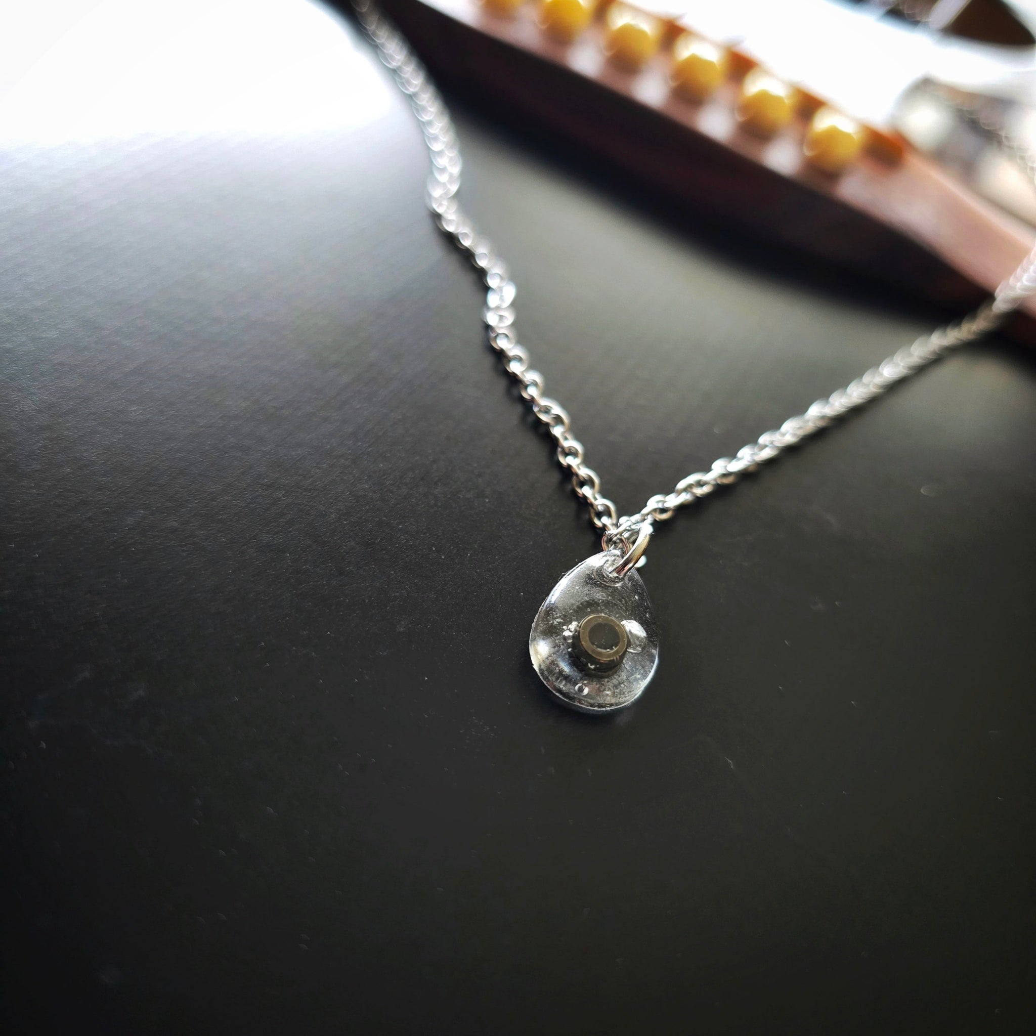 Close-up of Black Ballend Teardrop Resin Necklace on Black Guitar