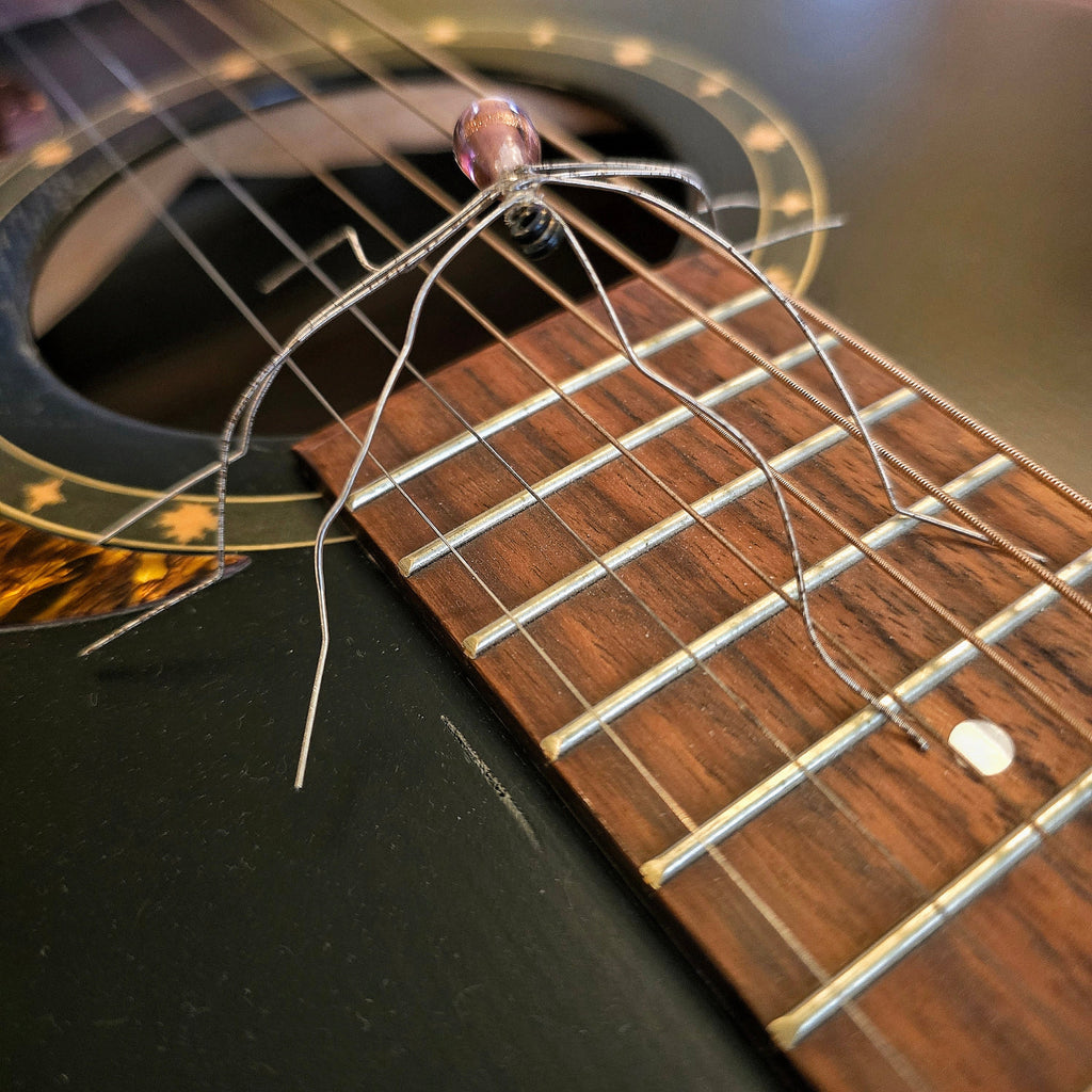 Close-up of a guitar's soundhole with a guitar string spider on the strings