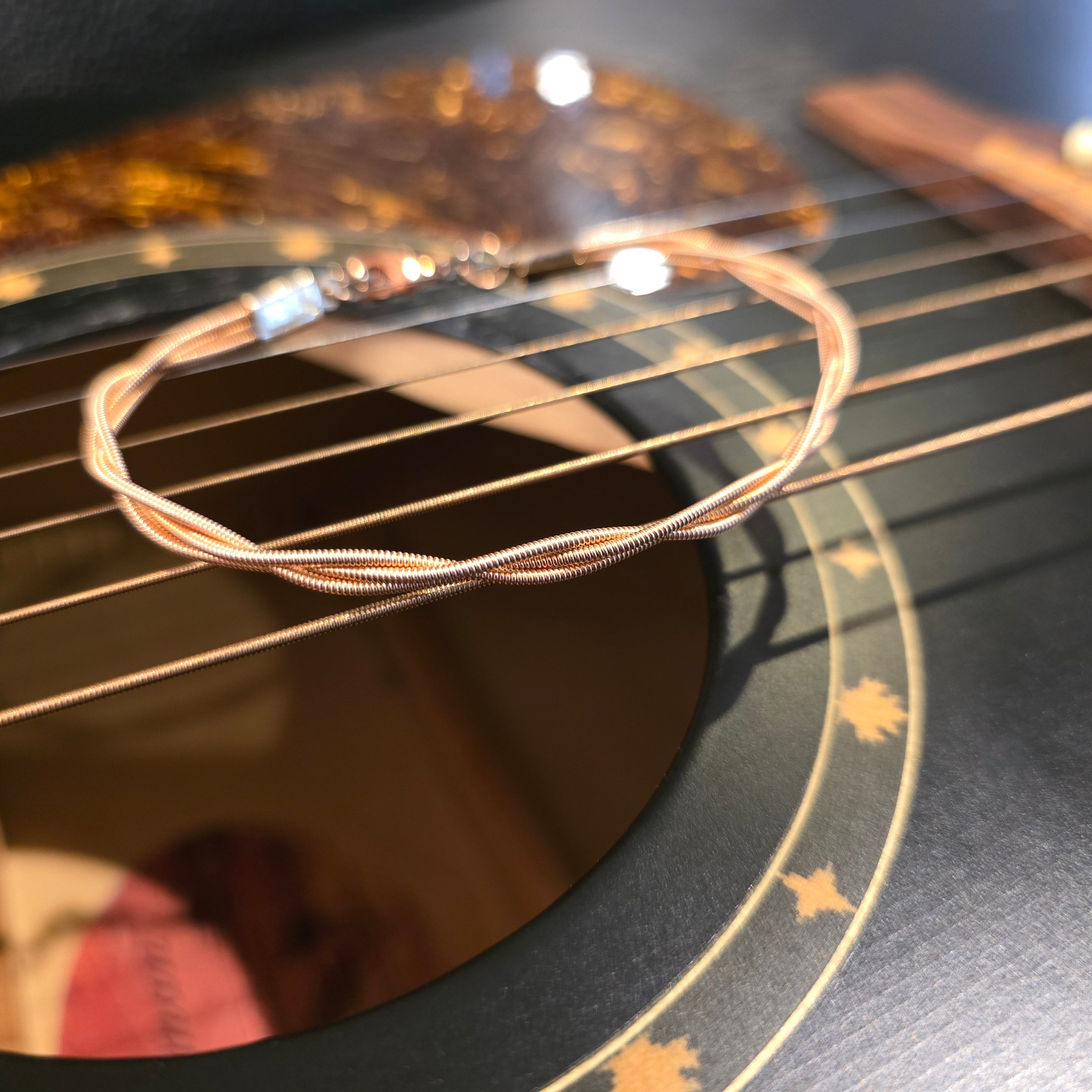 Close-up of a guitar string bracelet on a guitar body with a blurred background