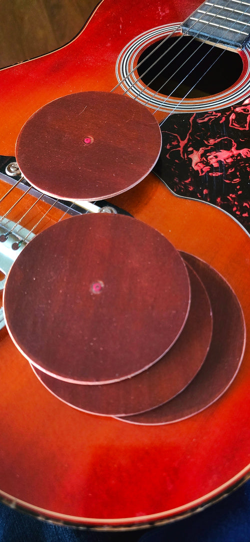 Four round coasters made from guitar wood on a guitar 