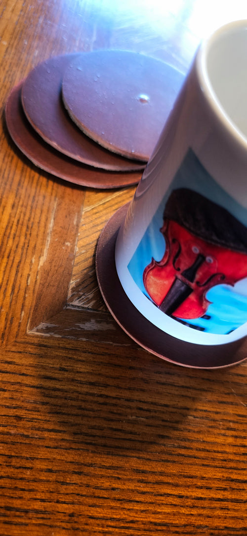 Four round coasters made from guitar wood one with a mug on it.