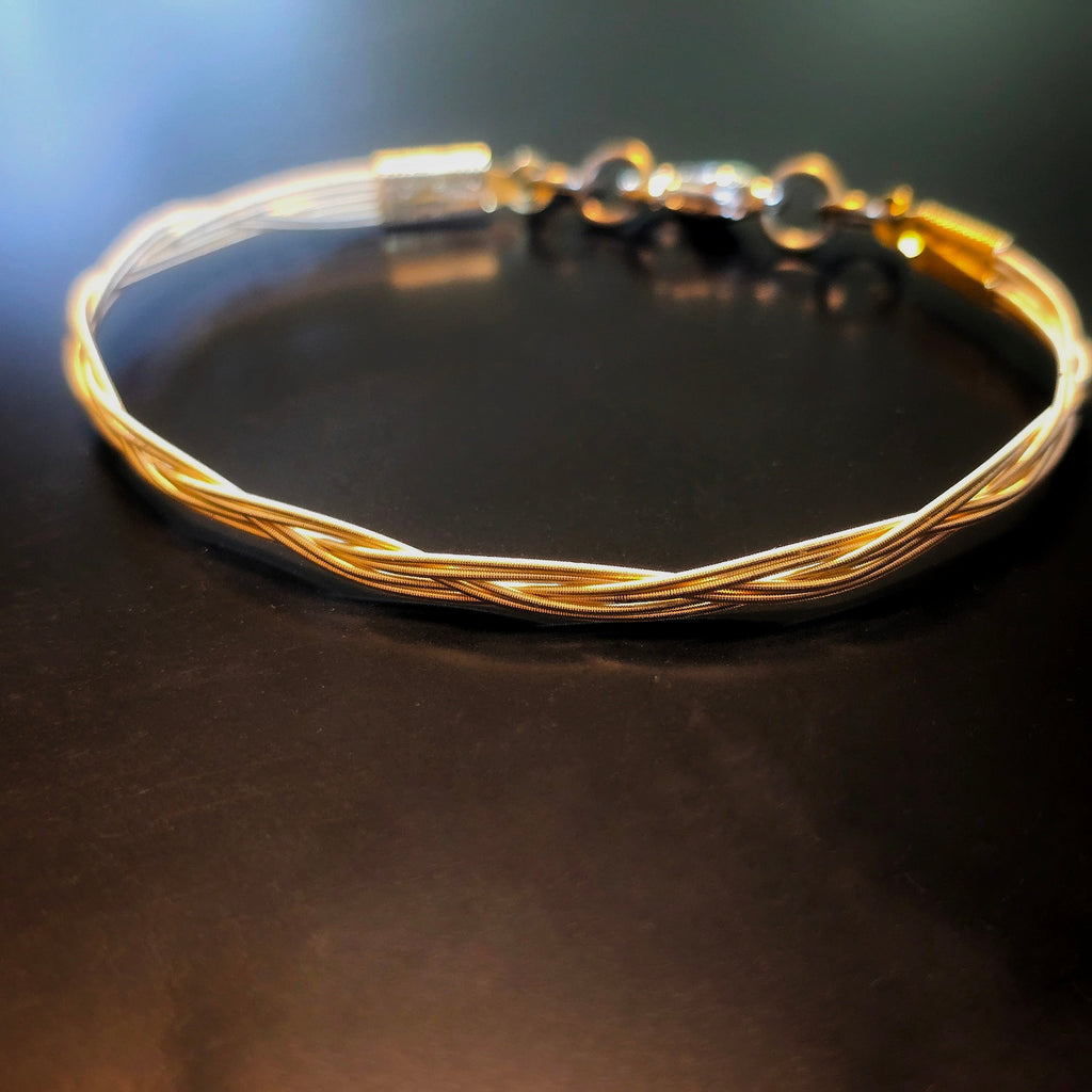 Gold Coloured Guitar String braided bracelet on a dark surface