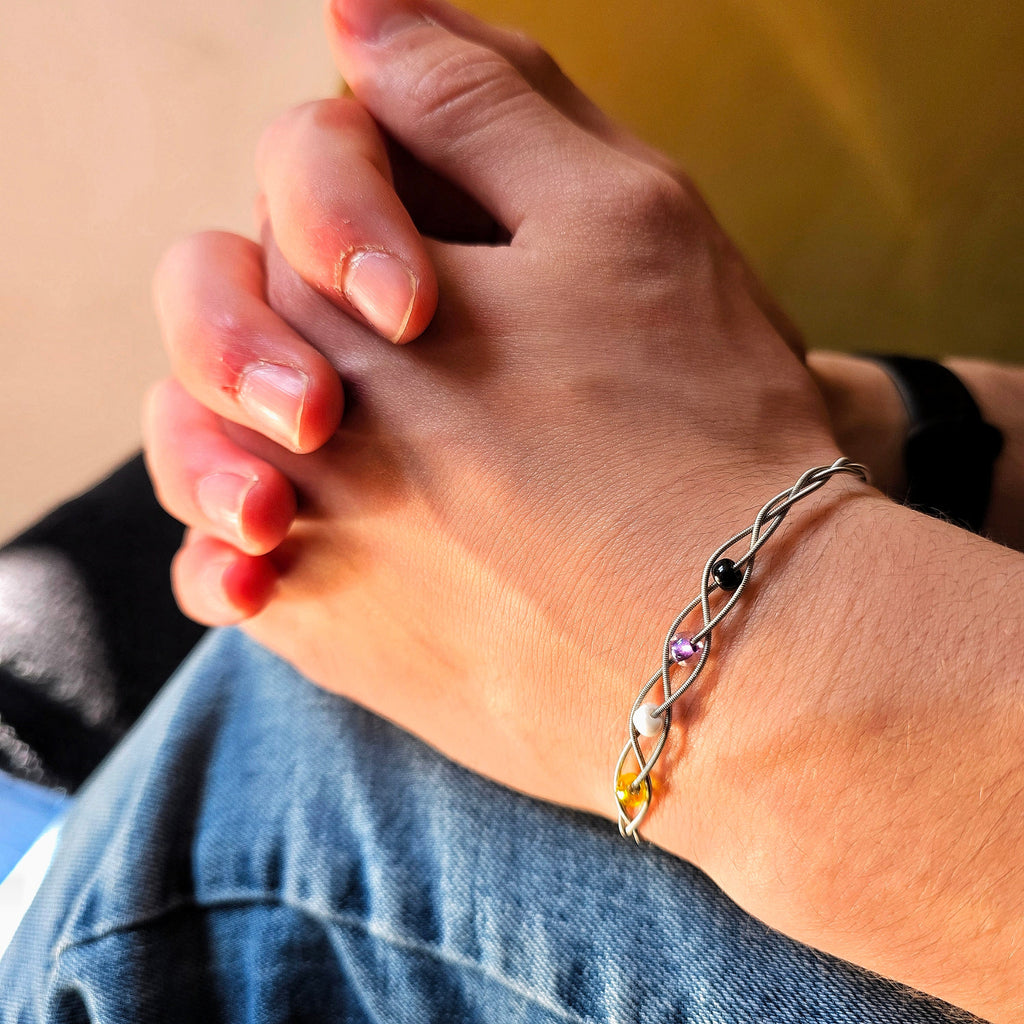 Two hands fingers intertwined wearing Non-Binary Pride Three Guitar String Braided Clasp Bracelet