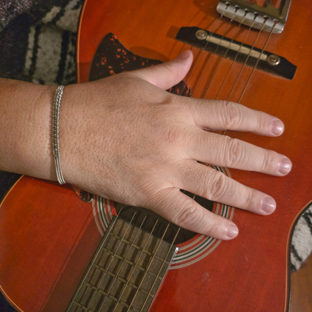 Hand on a guitar wwith a close-up view of the fretboardth guitar string bracelet 