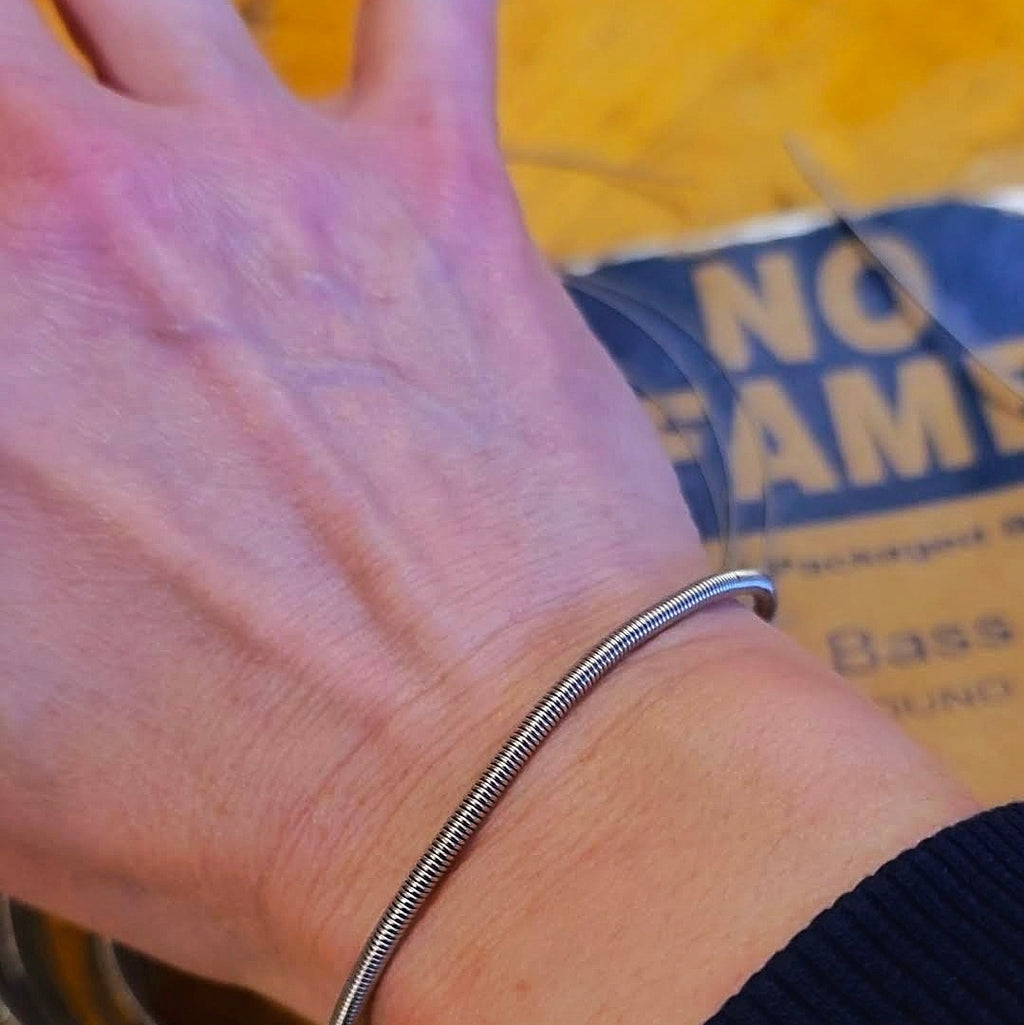 Hand wearing a bass string bracelet with a blurred background 