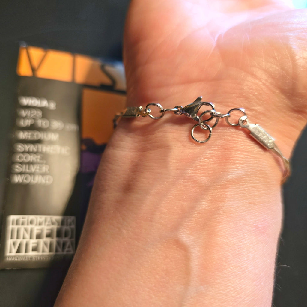 Hand with an Upcycled Viola String Bracelet view of clasp and extra loops (viola string package in background)